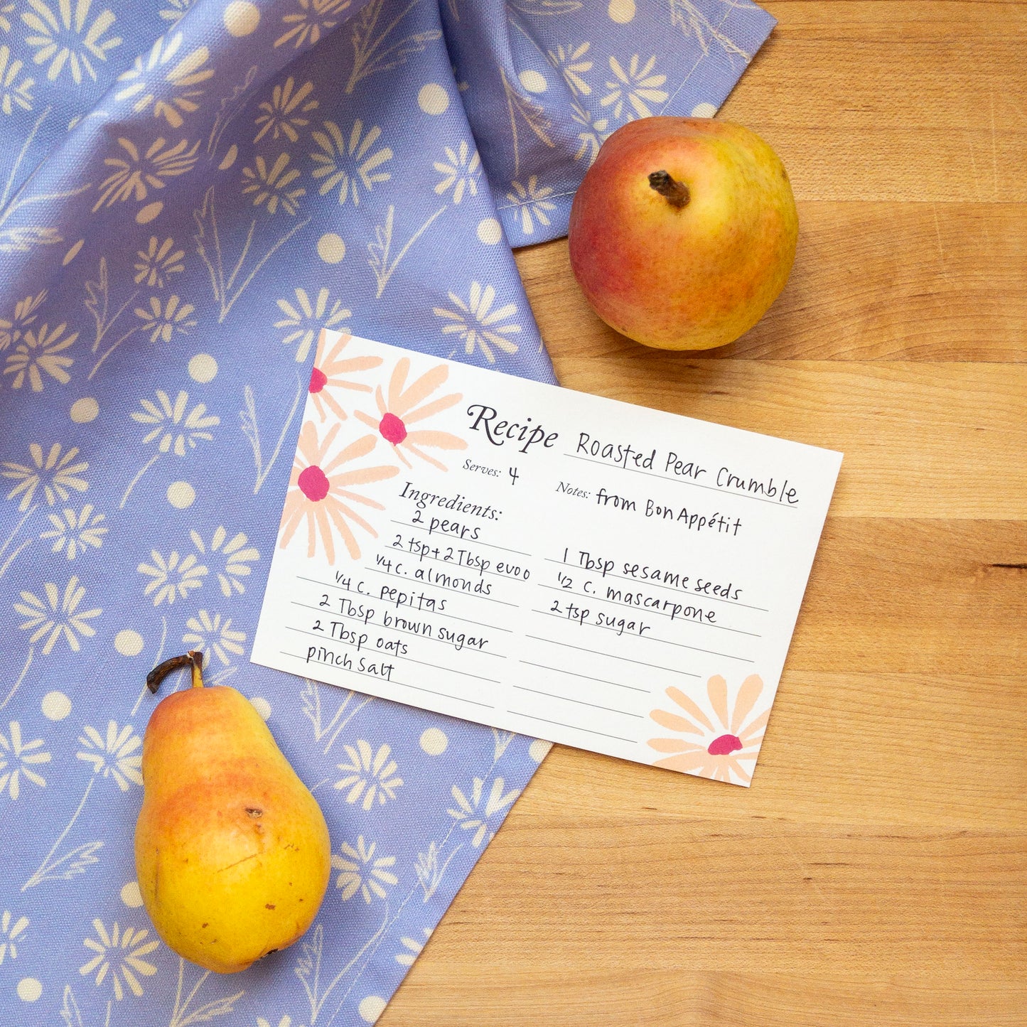 Roasted pear crumble recipe card with pears on a wooden surface and floral cloth