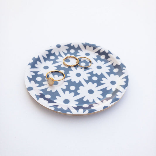 Round blue and white floral patterned coaster with gold rings on a white background