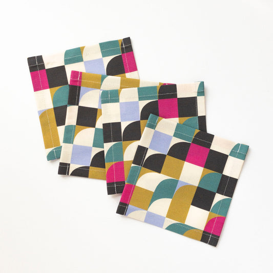 Set of four geometric patterned cocktail napkins on a white background