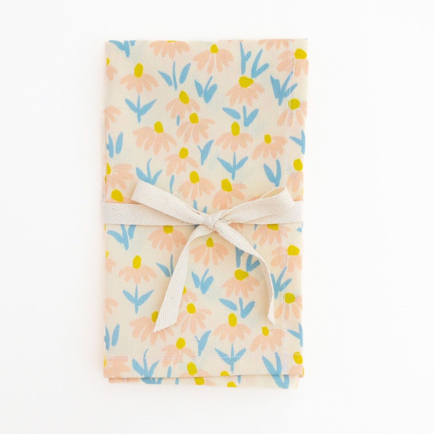 Floral patterned tea towel wrapped with a white ribbon on a white background.