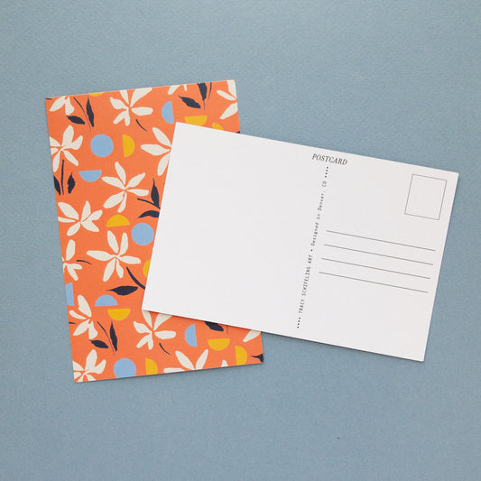 Red floral postcard and blank postcard back arranged on a blue background.