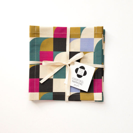 Pack of colorful cocktail napkins with a decorative bow on a white background
