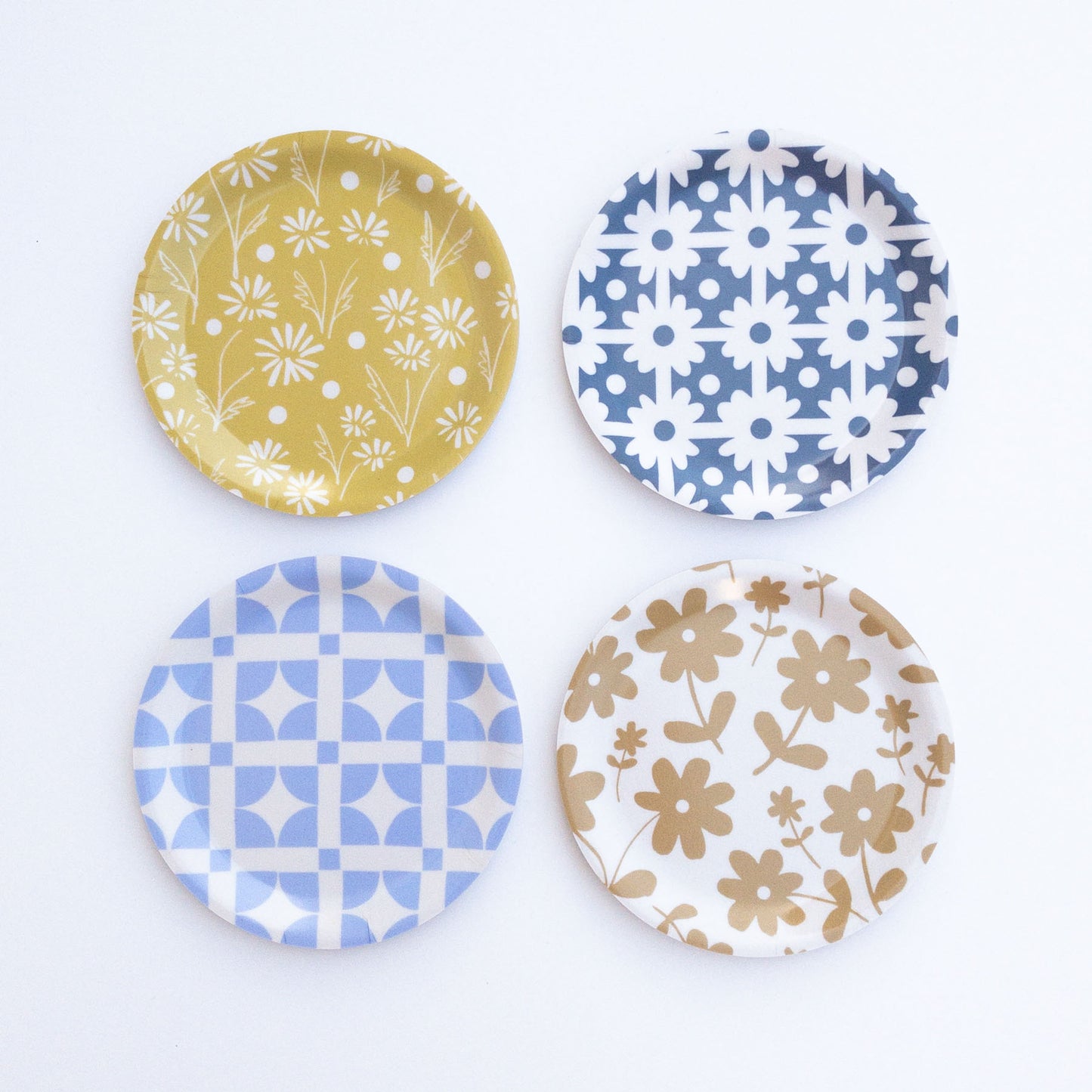 Four round coasters with floral and geometric patterns on a white background