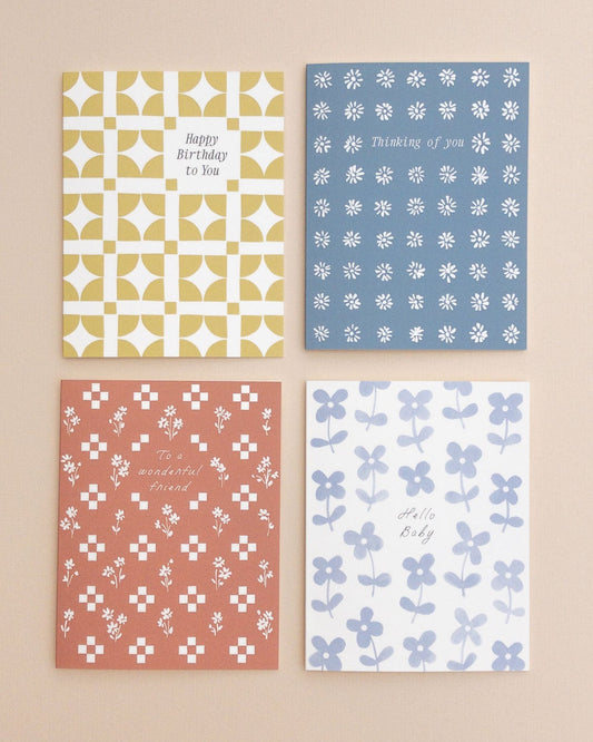 Four patterned greeting cards on a beige background