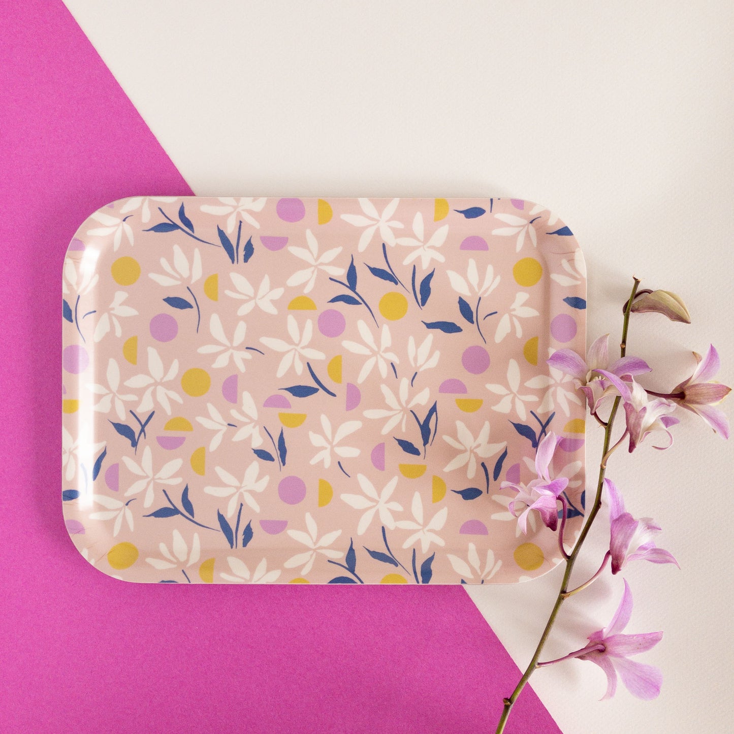 Pink floral tray next to purple flowers.