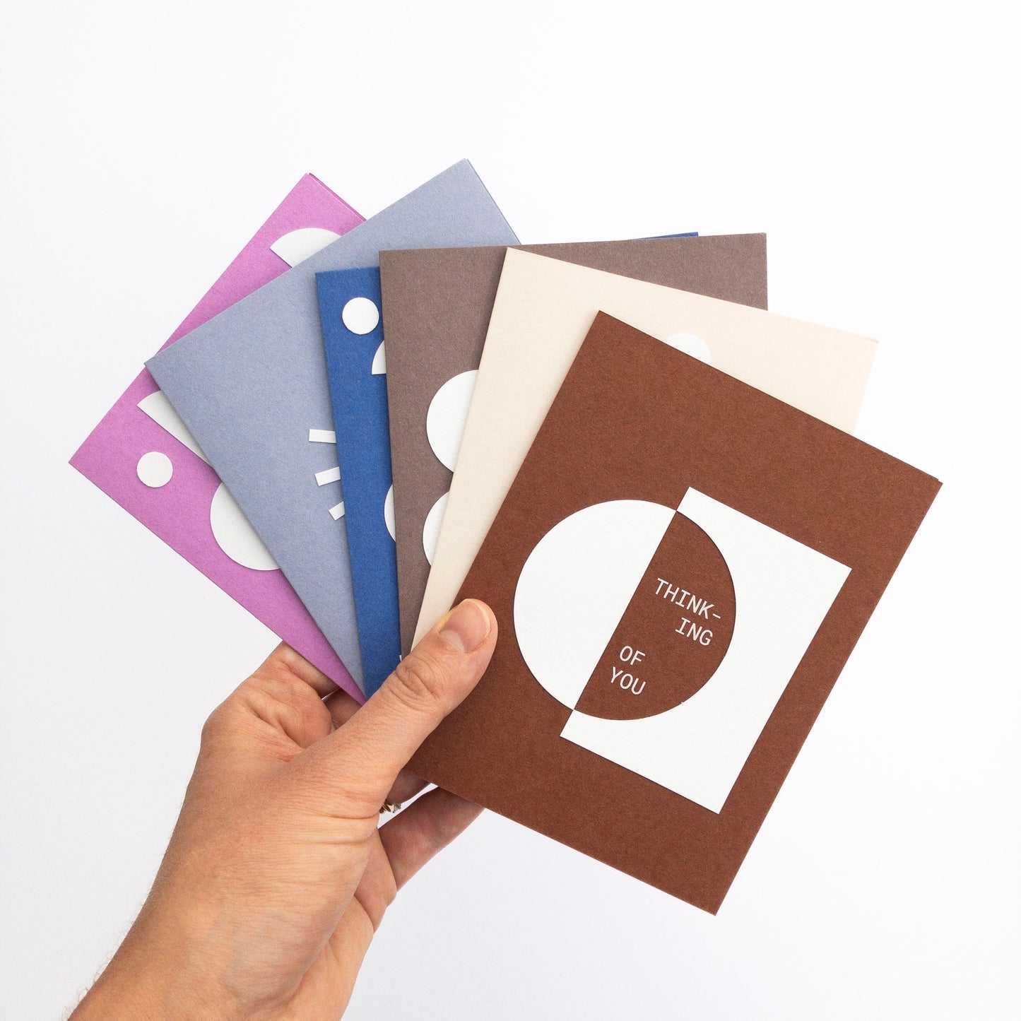 Hand holding a brown card with text among other cards on a white background
