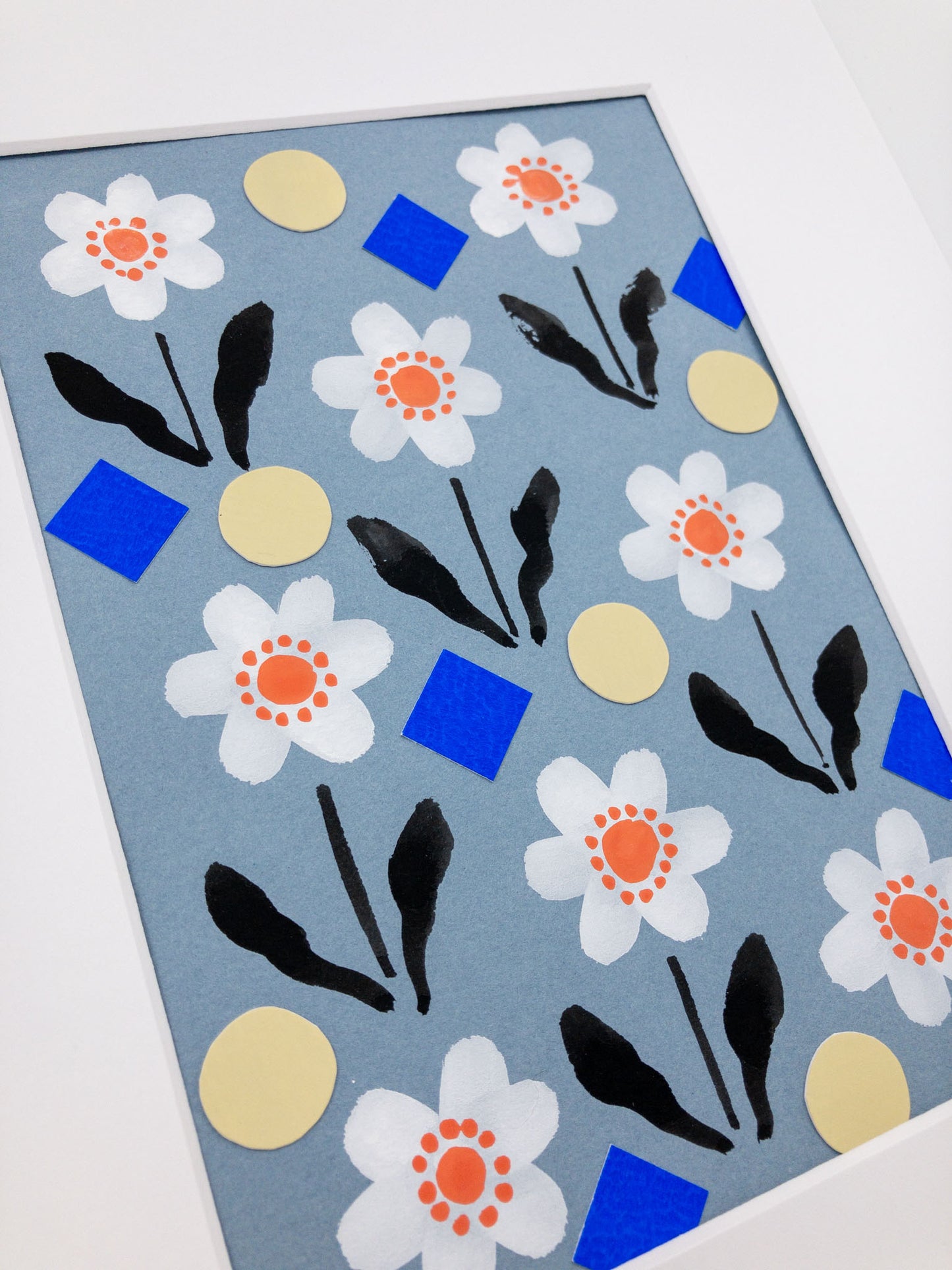 Angled photo showing the 3d texture of a floral and geometric collage featuring daisies, yellow circles, and blue squares.