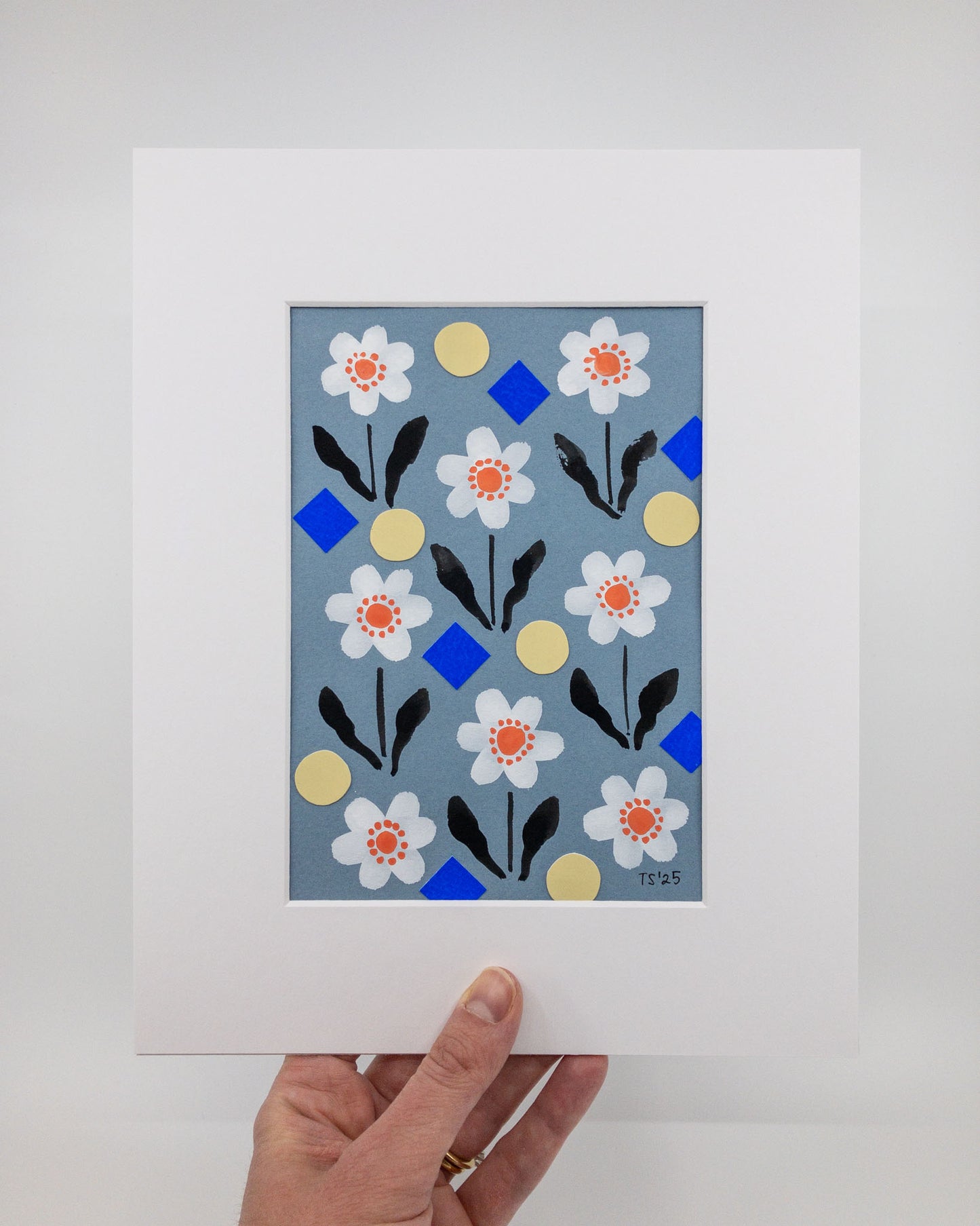 Floral and geometric collage featuring daisies, yellow circles, and blue squares in a white mat.