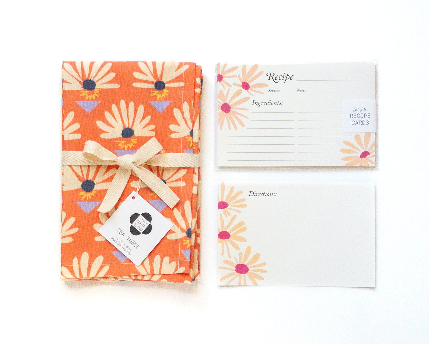Floral-patterned tea towel with a bow, accompanied by recipe cards on a white background.