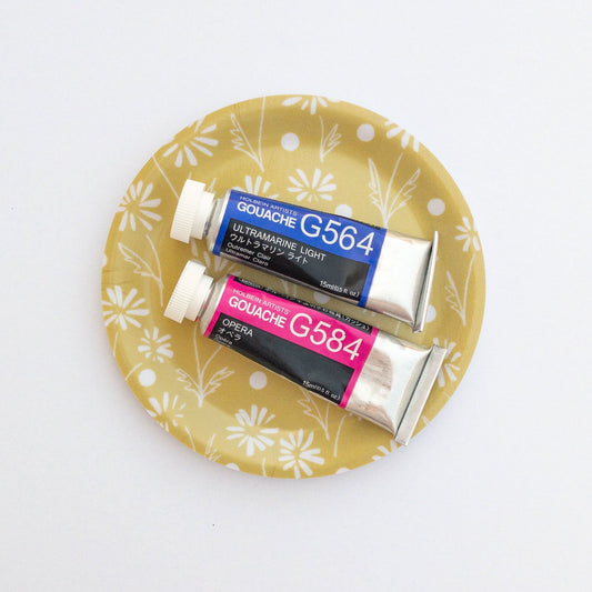 Two tubes of Gouache paint on a yellow daisy coaster with floral pattern