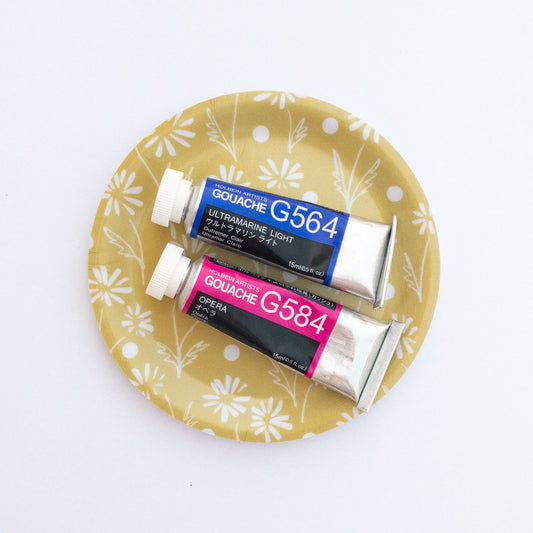 Two tubes of Gouache paint on a yellow daisy coaster with floral pattern