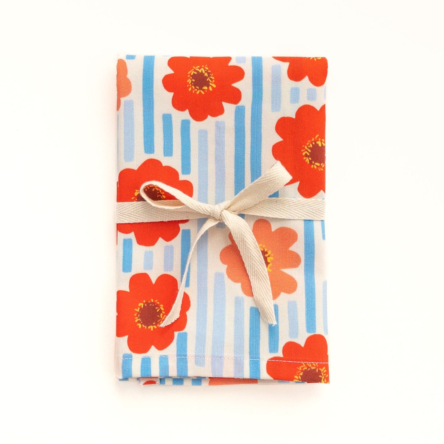 Tea towel with floral zinnia design and striped pattern on a white background.