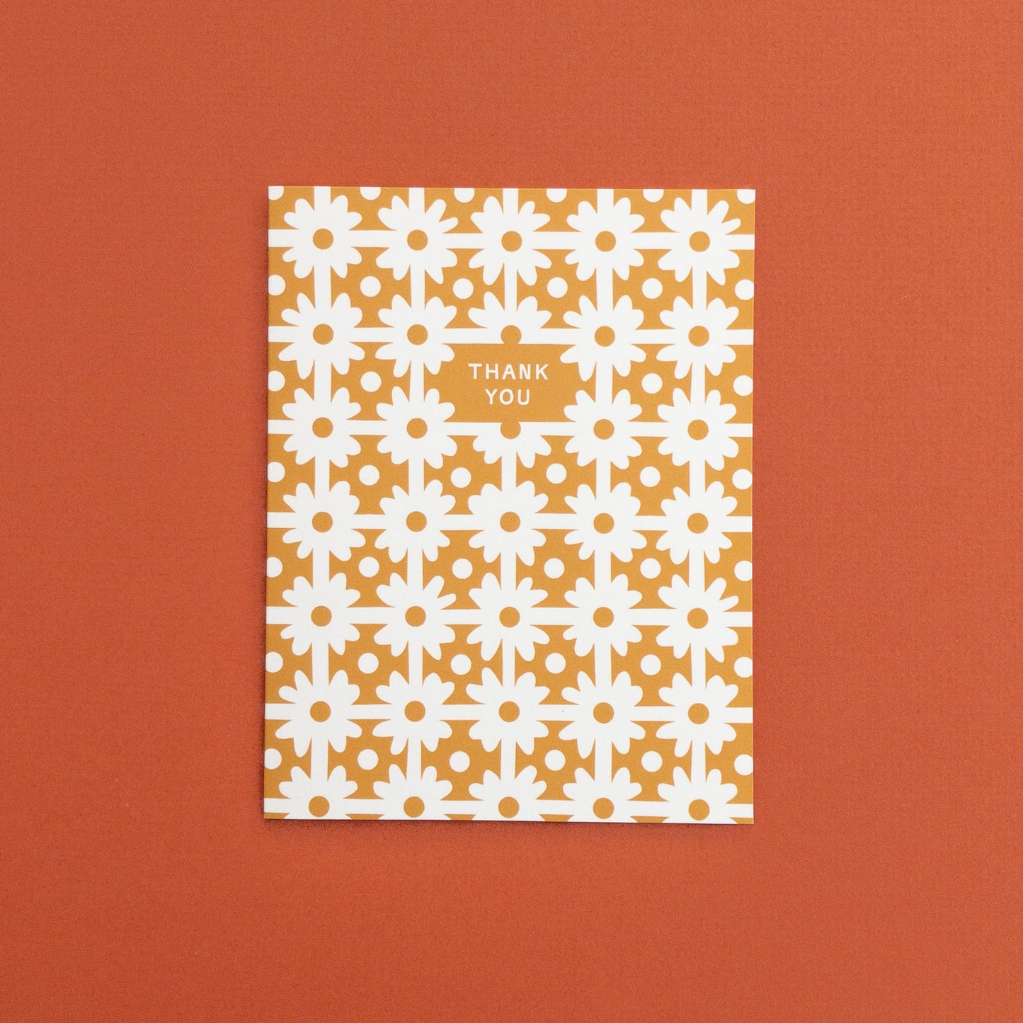 Greeting card with white floral pattern on gold background and text 'Thank You' 
