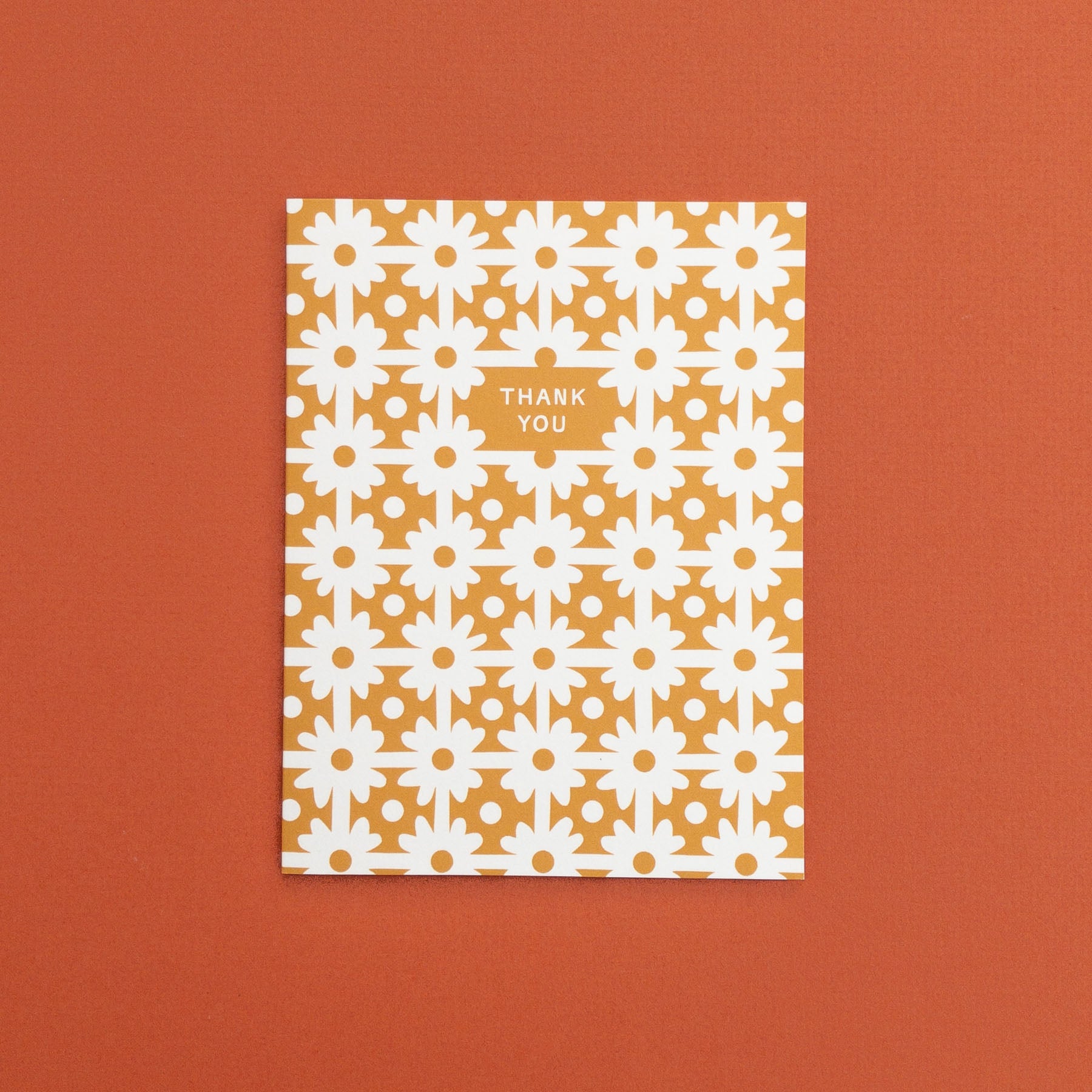 Greeting card with white floral pattern on gold background and text 'Thank You' 