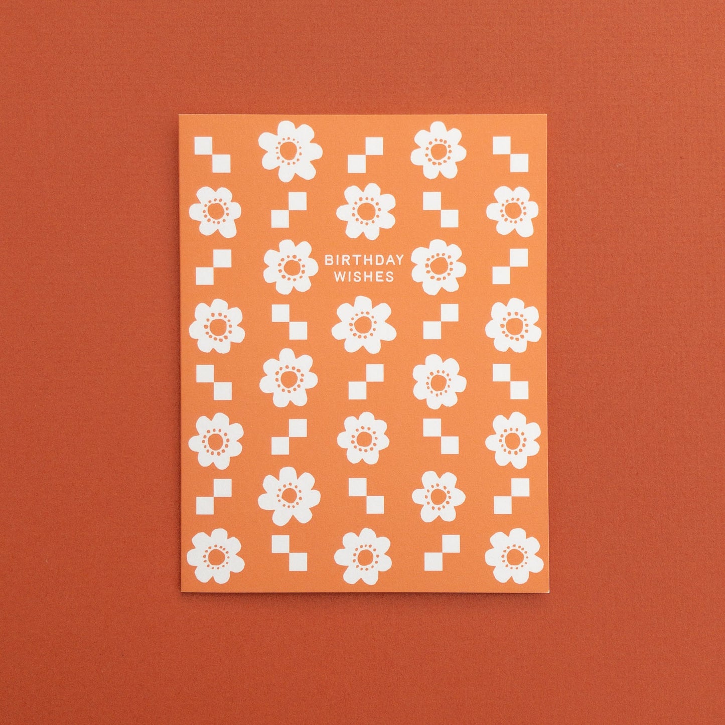 Greeting card with white floral pattern and 'Birthday Wishes' text on an orange background