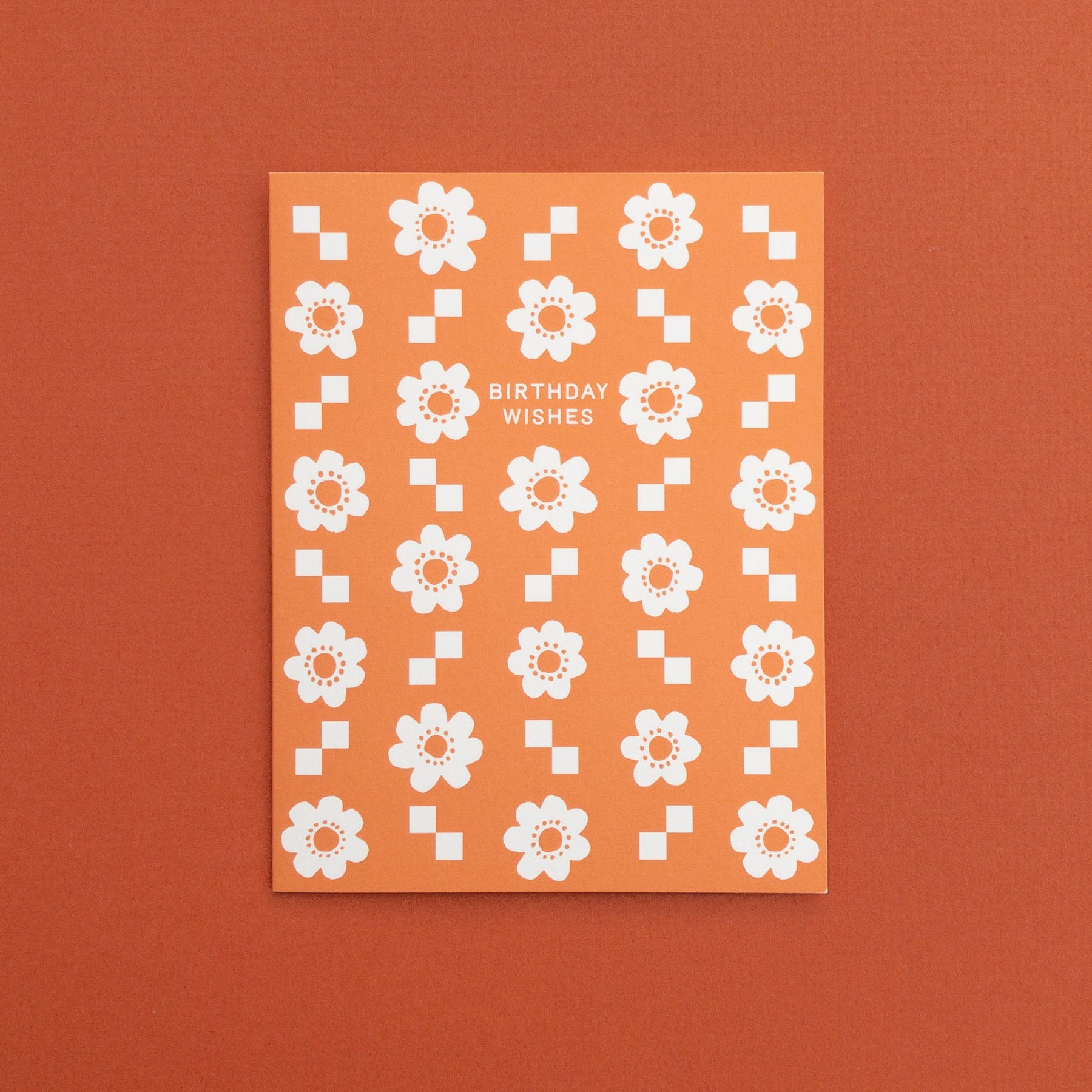 Greeting card with white floral pattern and 'Birthday Wishes' text on an orange background