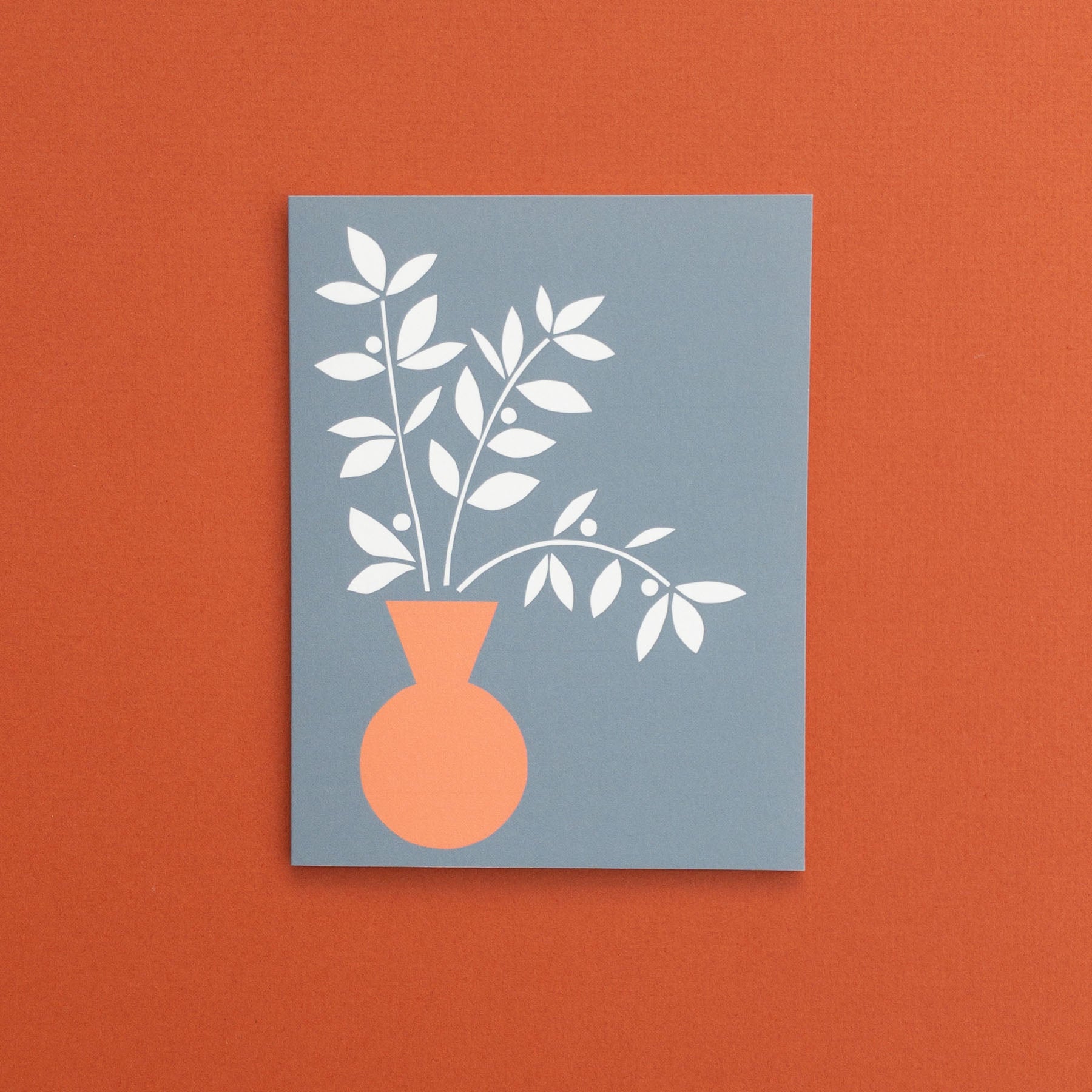 Blank botanical greeting card with an orange vase and white leaves on a slat blue background.