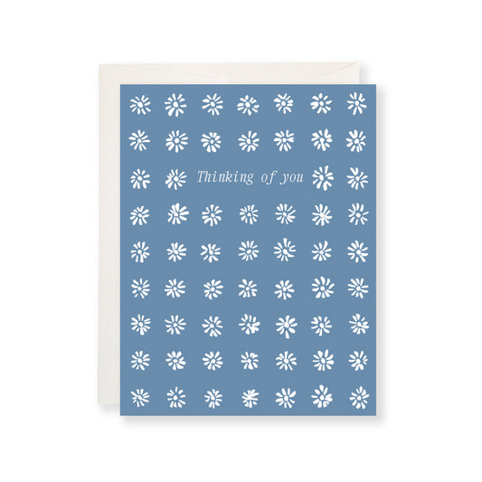 Blue card with white floral pattern and 'Thinking of you' text on a white background