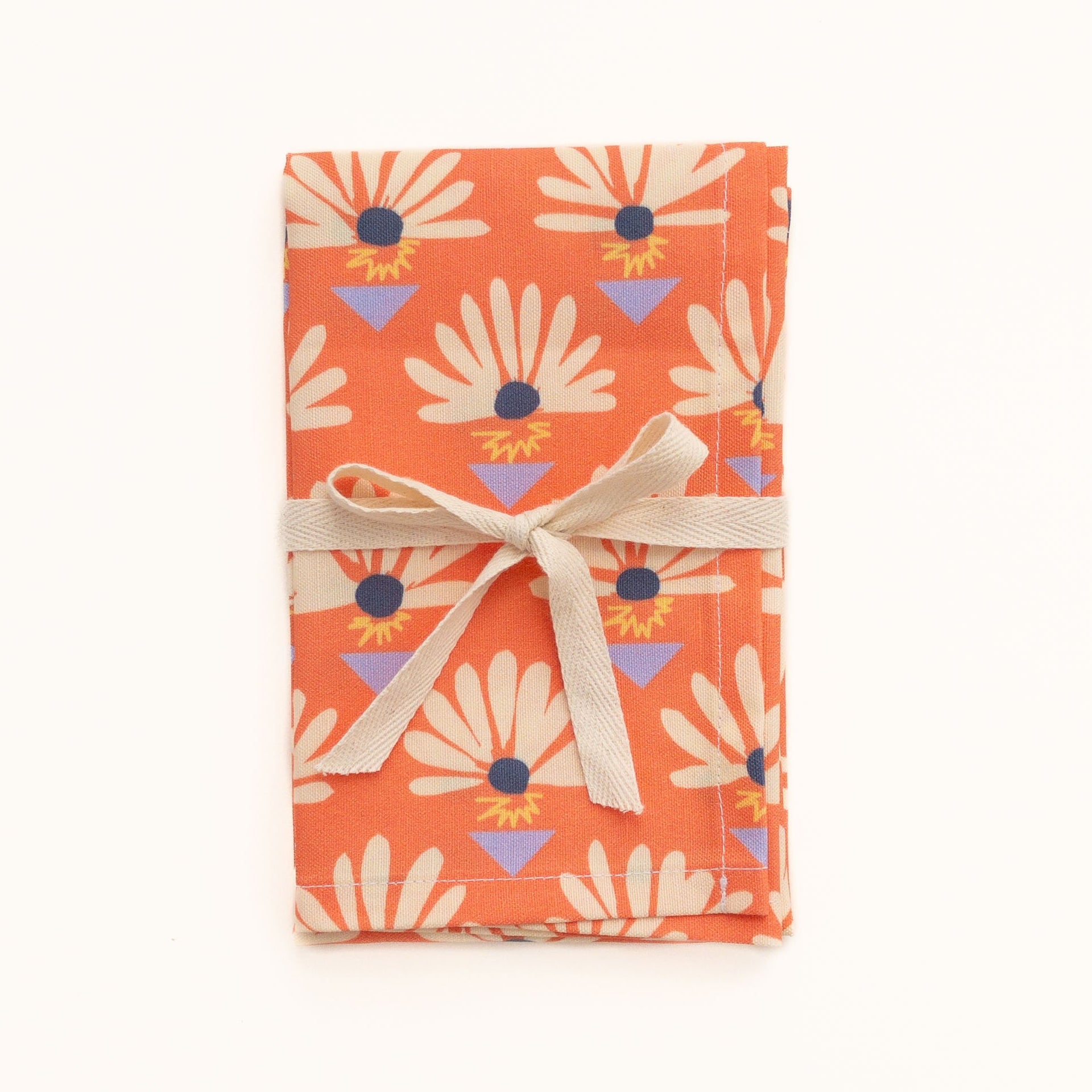 Orange red tea towel featuring a floral pattern wrapped in a ribbon on a white background.