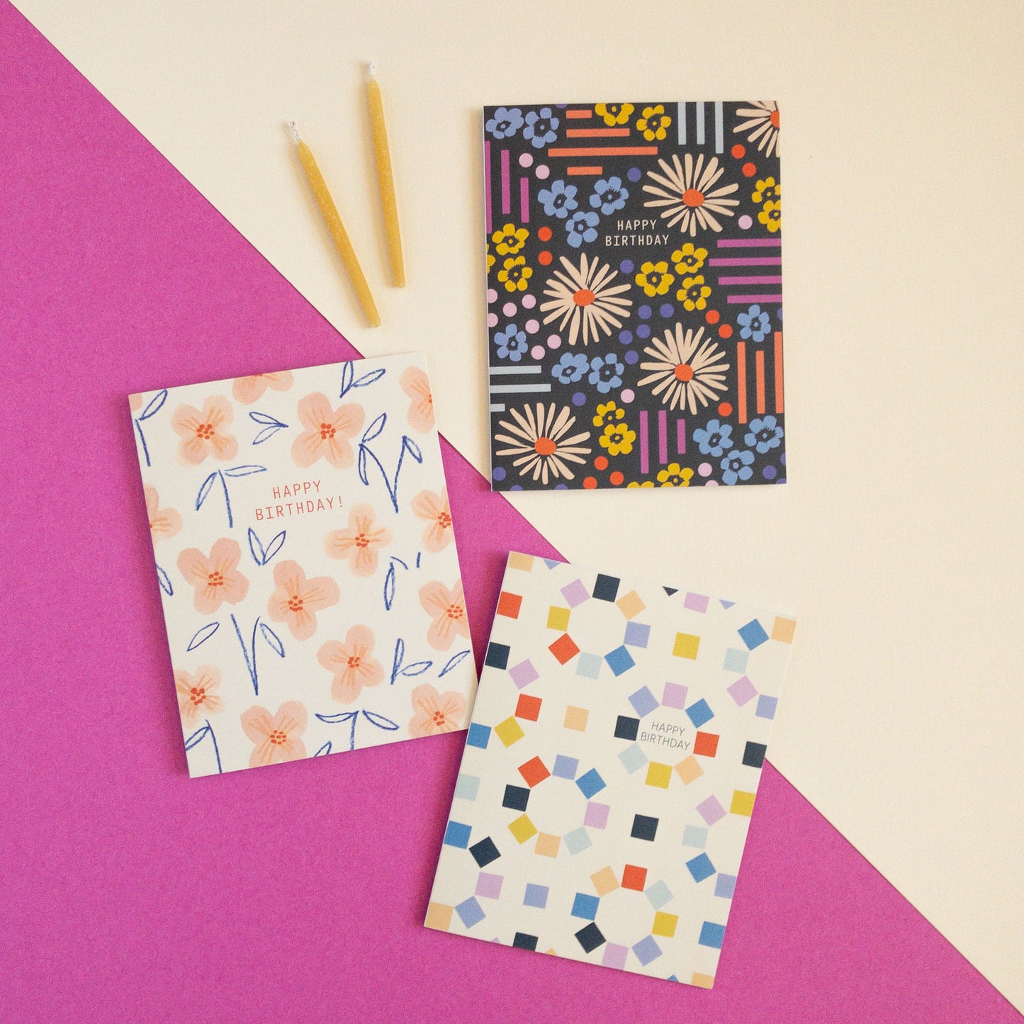 Three colorful birthday cards on a pink and white background with two candles.