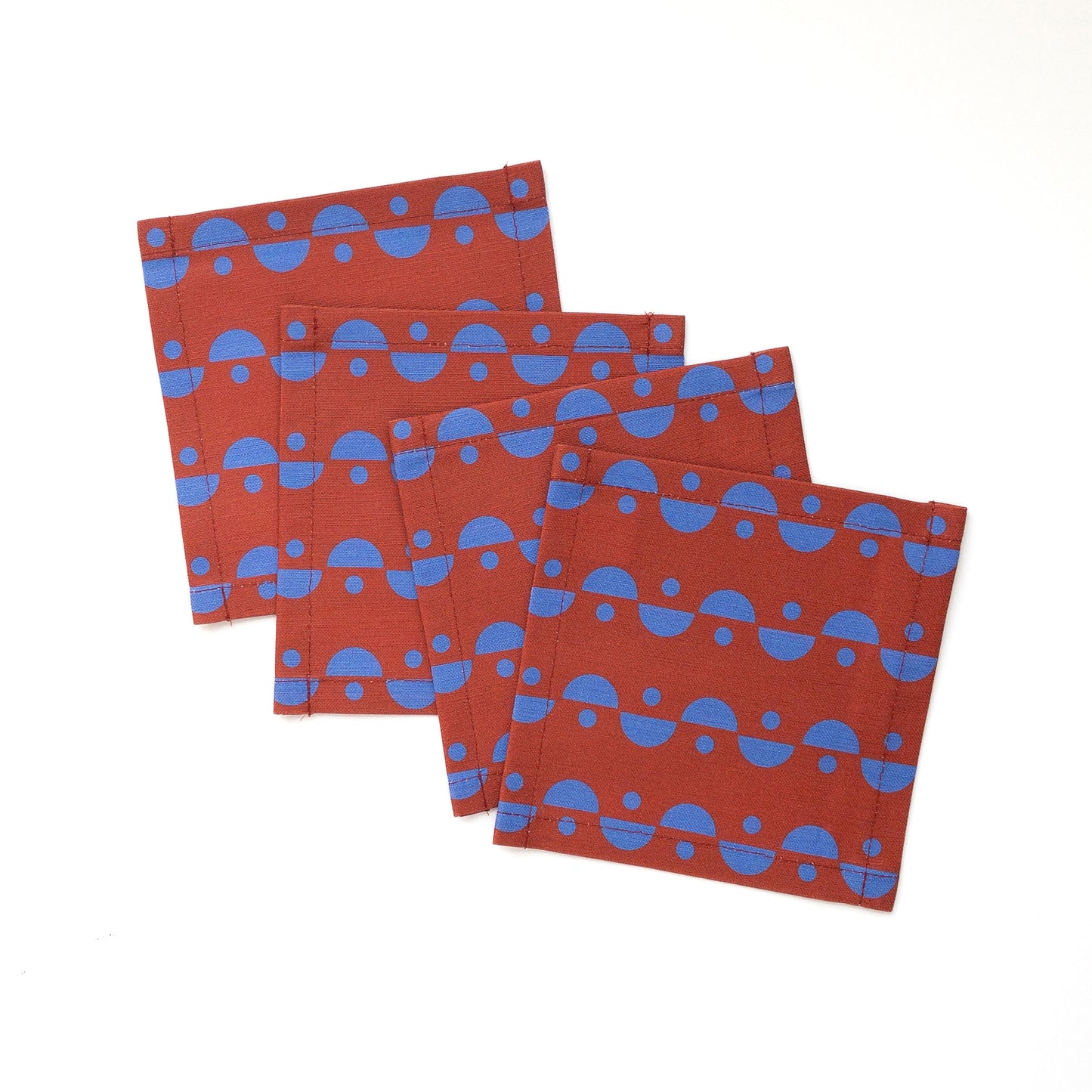 Set of four blue and brown cocktail napkins on a white background