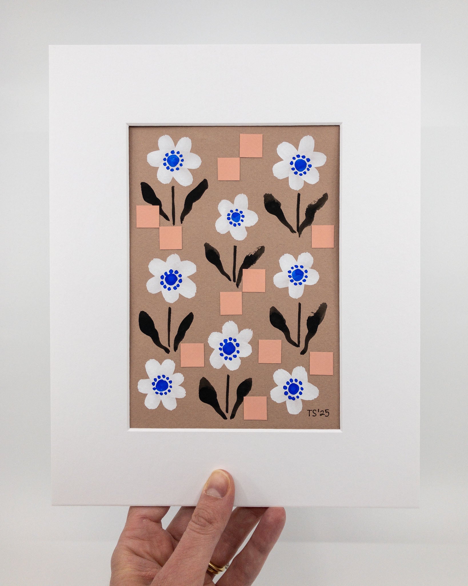 Floral artwork featuring white flowers on a brown background with a repeating square motif. The artwork is in a white mat.