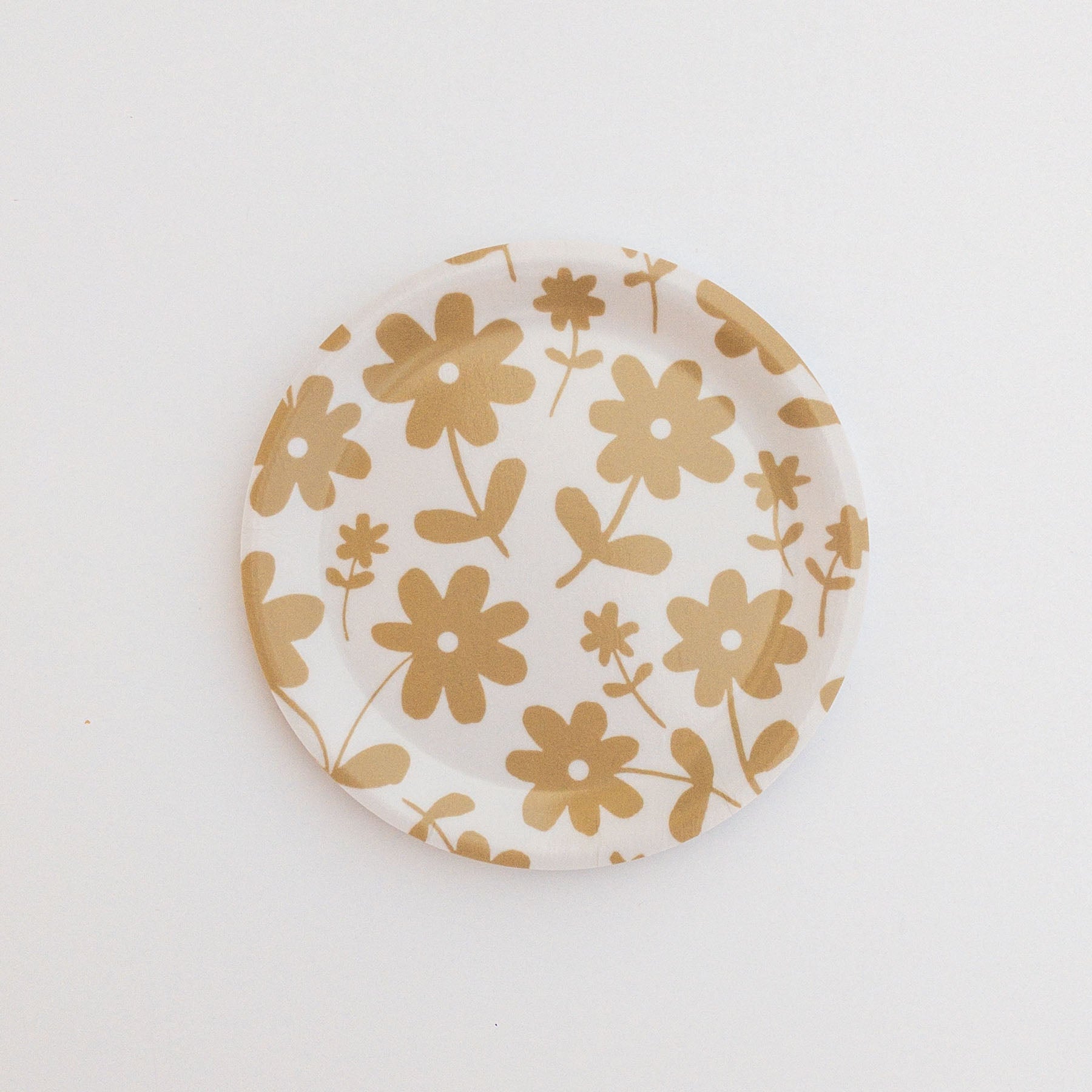Round coaster featuring a gold floral pattern on a white background.