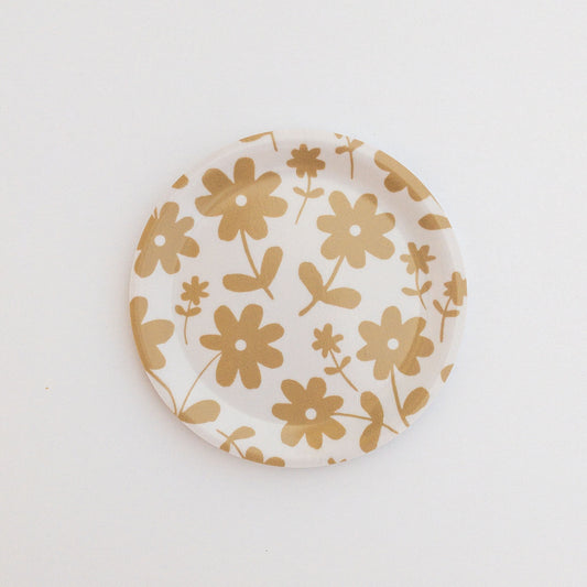 Round coaster featuring a gold floral pattern on a white background.