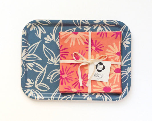 Set of colorful cocktail napkins tied with a ribbon on a blue tray with floral pattern