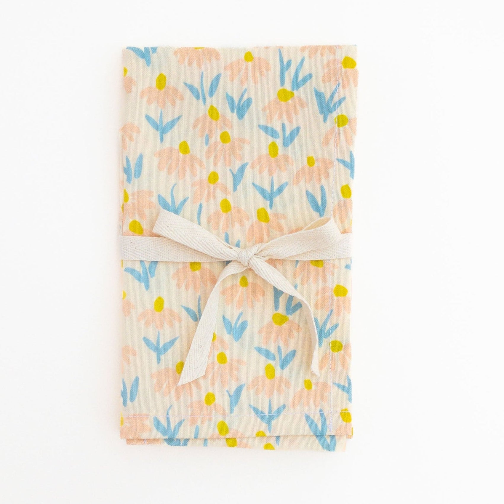 Floral patterned tea towel wrapped with a white ribbon on a white background.