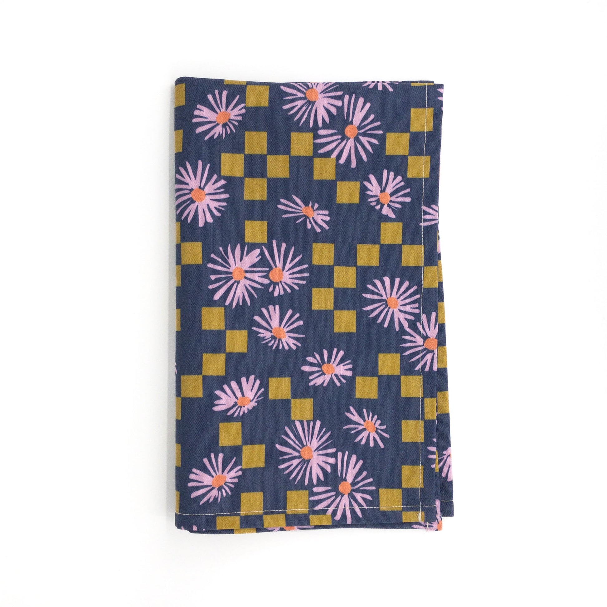 Modern floral tea towel featuring a pattern of purple daisies and olive squares, folded on a white background.