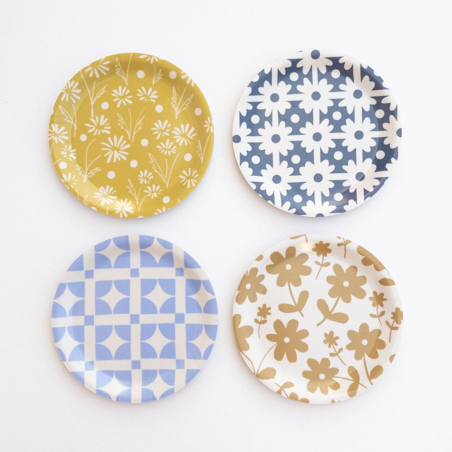 Four round coasters with floral and geometric patterns on a white background