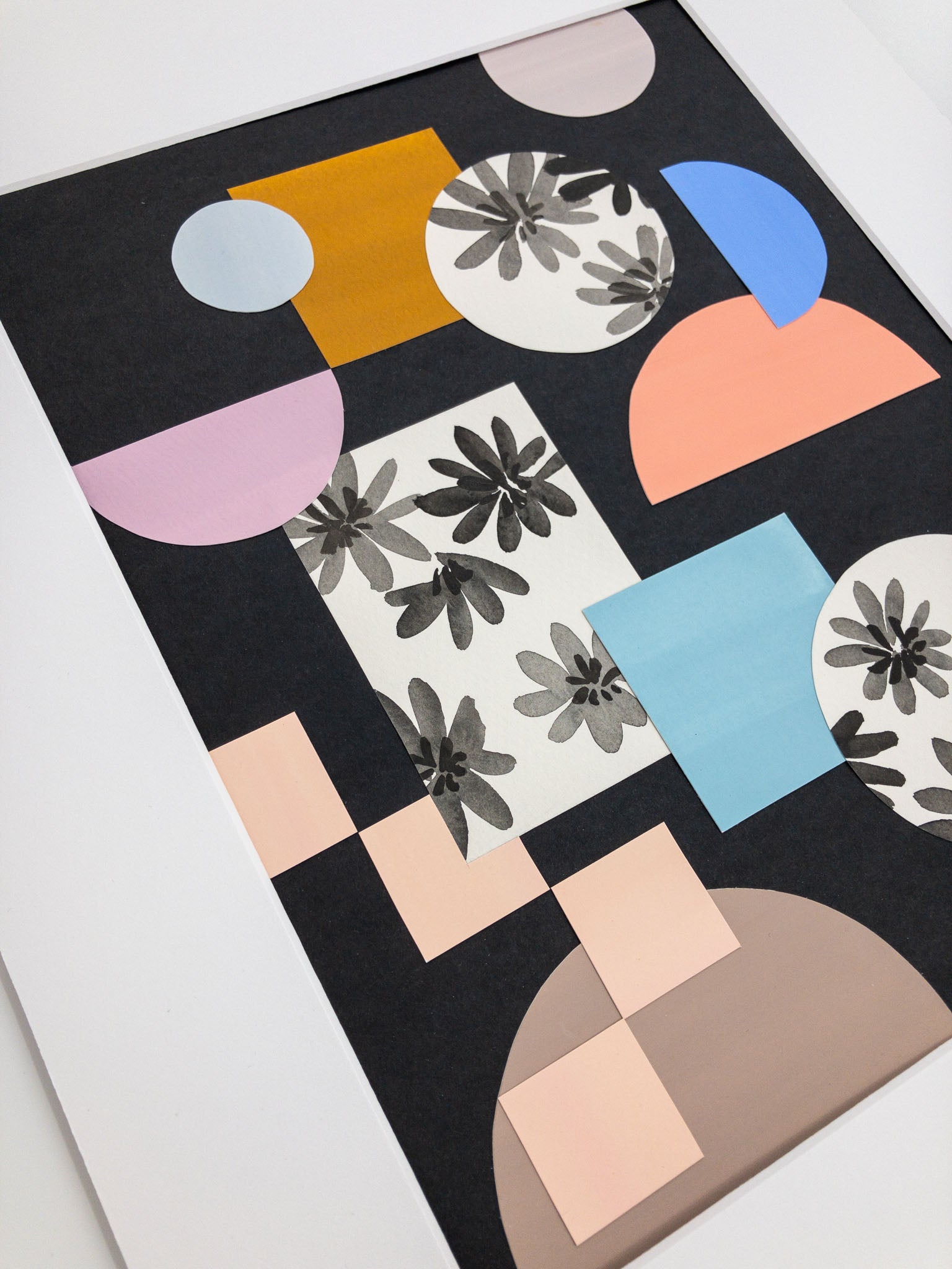 Angled photo of colorful shape collage on black paper.