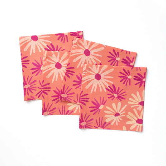 Set of four pink cocktail napkins with floral pattern on a white background