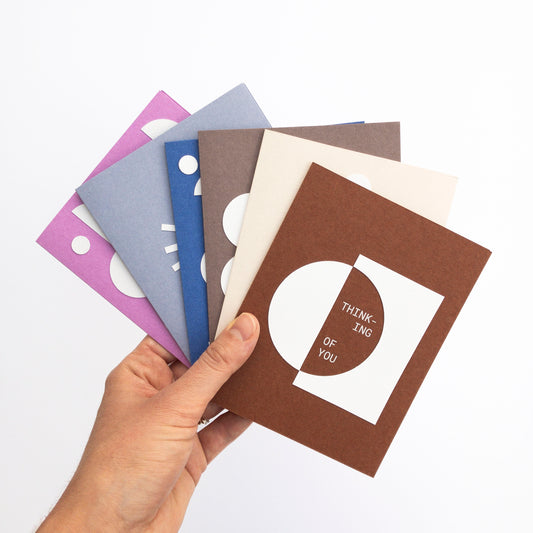 Hand holding a brown card with text among other cards on a white background