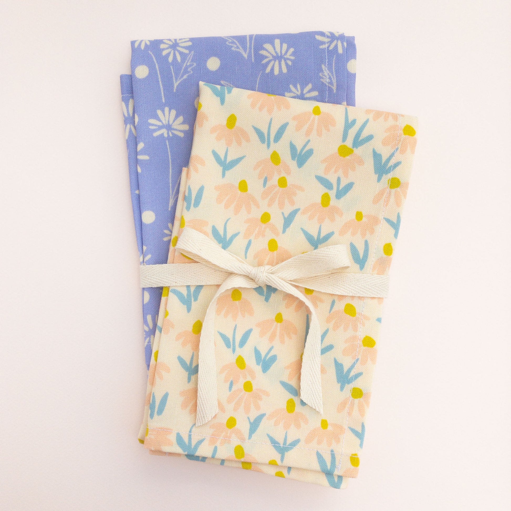 Two floral tea towels tied with a ribbon on a white background.