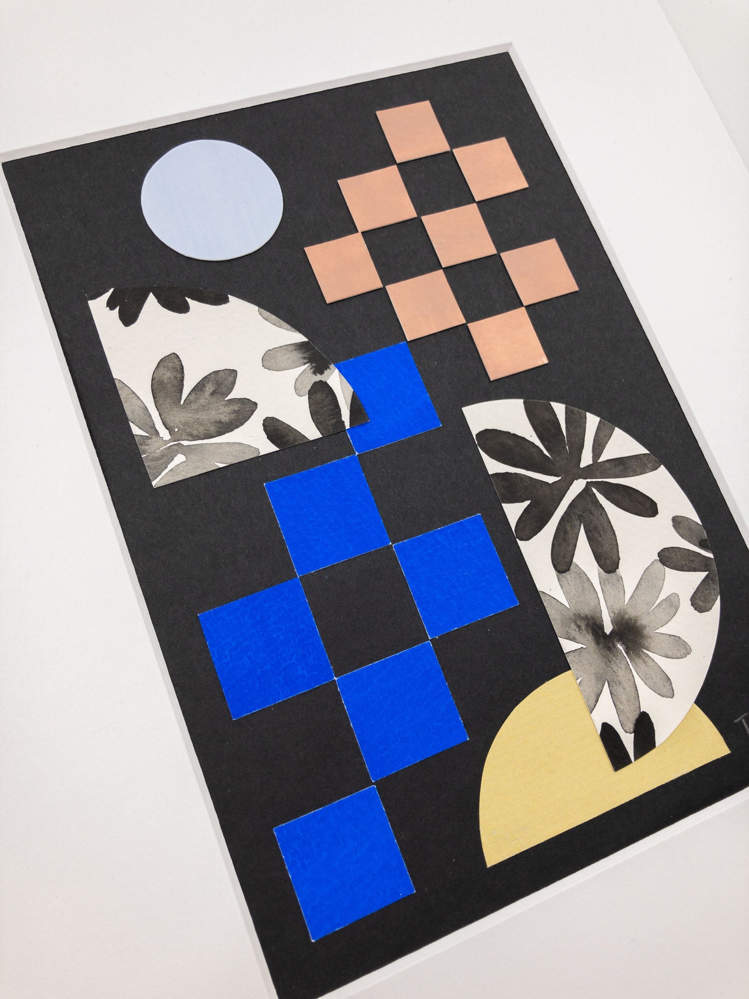Angled photo of a geometric and floral collage on a black background.