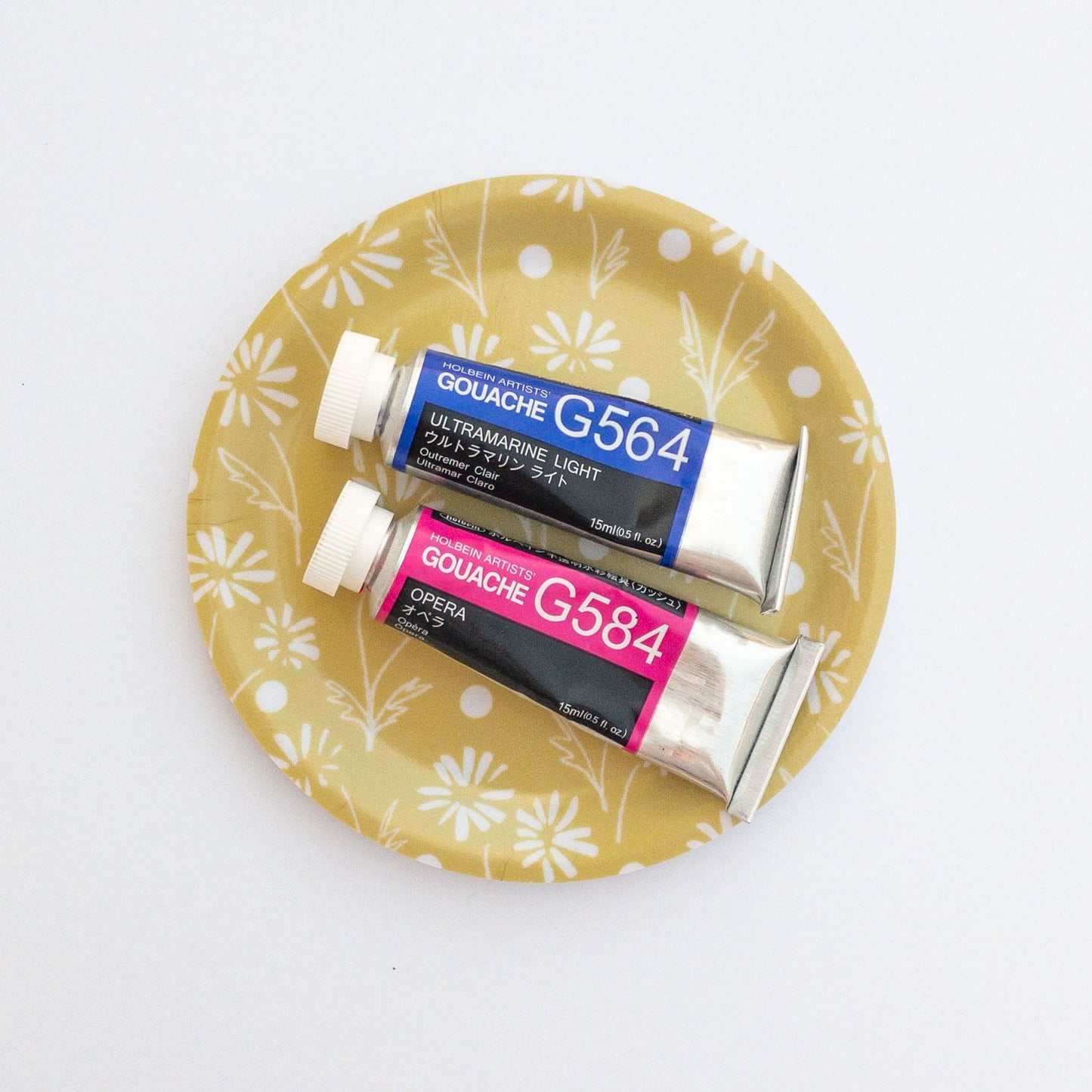 Two tubes of Gouache paint on a yellow daisy coaster with floral pattern