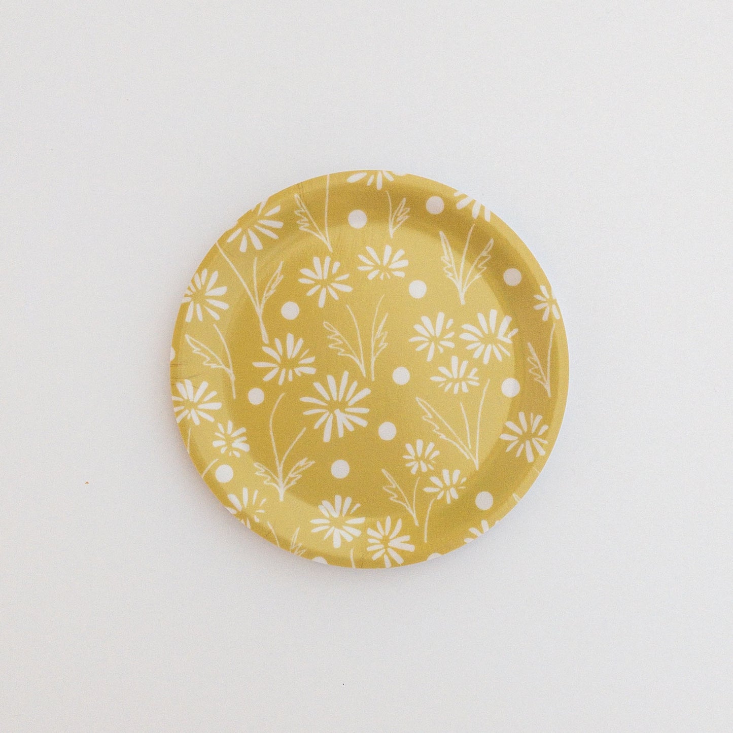 Yellow coaster with white floral pattern on a white background