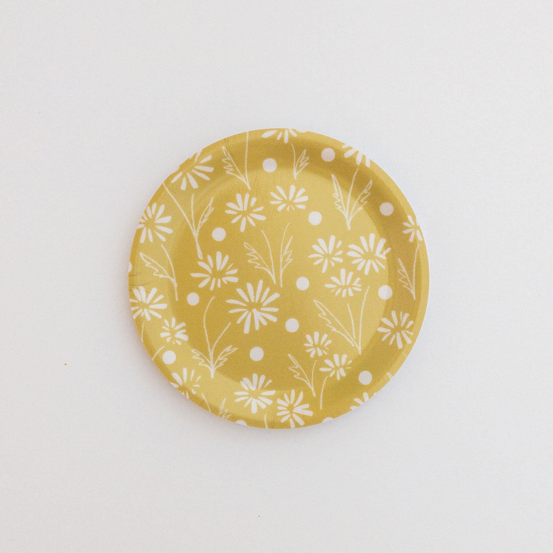 Yellow coaster with white floral pattern on a white background