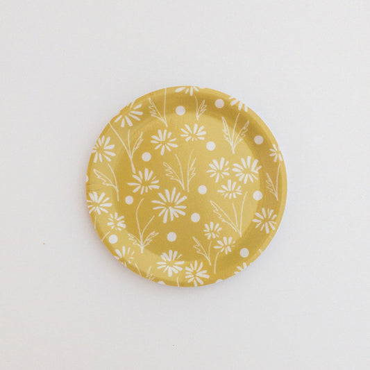 Yellow coaster with white floral pattern on a white background