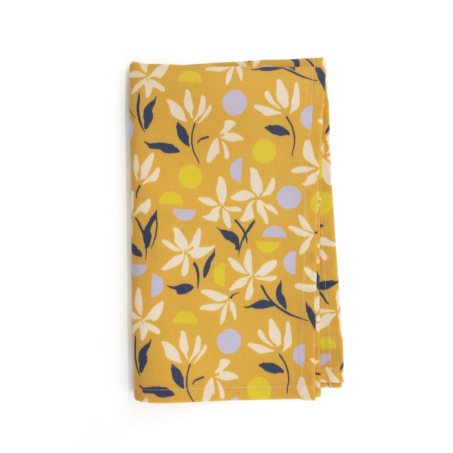 Folded yellow floral tea towel on a white background.